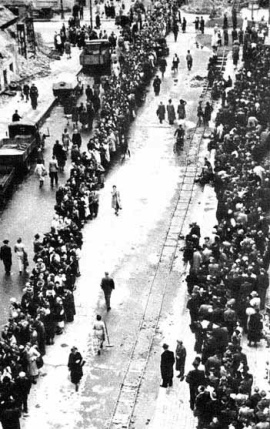 Der Rossmarkt von
                        Frankfurt am Main nach Kriegsende 1945 mit
                        Schlangestehen und mit den Geleisen einer
                        Trümmerbahn