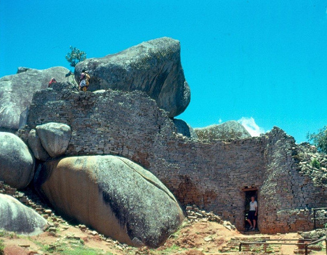 La ruina en la acrópolis con la
                            entrada y las piedras gigantes con personas
                            adultas, primer plano