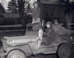 General
                Patton upright in a Jeep greeting his troops in
                Normandy, 1944