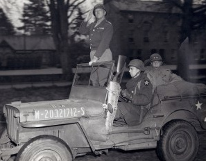 General Patton in his jeep upright
                                saluting his troops in Normandy, 1944
