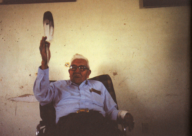 Noble Red Man
                (Mathew King) im Stuhl mit Feder in der Hand, 1987 ca.