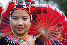 Mdchen der Meo (Hmong) in Thailand in
                        traditionellen Kleidern und mit einem roten
                        Regenschirm