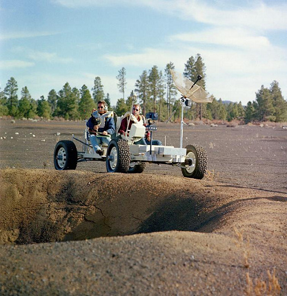 Irwin (izquierda) y Scott (derecha) con el
                        carro lunar de entrenamiento (Lunar Roving
                        Vehicle Simulator, "1g trainer") en
                        una excursión geológica en un campo de cráteres
                        de Cinder Lake en Arizona al margen de un cráter
                        de 30 pies, 02-03/11/1970, foto 02