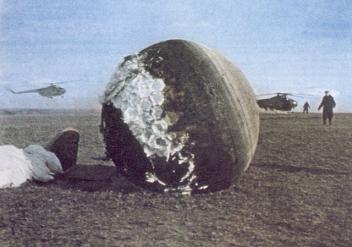 Gagarin's alleged landing capsule in
                            the field with helicopters. The abrasion
                            parts do not correspond with the other two
                            capsules [10].