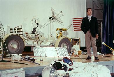 Training for Apollo 15, foto no. 71-HC-678:
                        Irwin explains at a press conference the LRV and
                        other "moon things" as the big
                        Hasselblad camera on the flor or the helmets
                        etc., 6. May 1971.