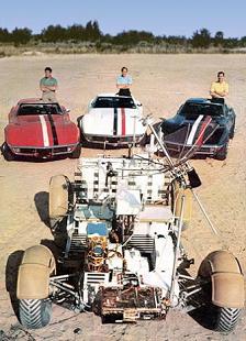 Training zu Apollo 15: Mondauto im
                        Vordergrund, im Hintergrund stehen die drei
                        Astronauten mit ihren Corvetten-Autos.