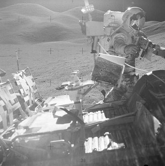 Mondlandung Apollo 15 Foto-Nr.
                        AS15-85-11492: Scott mit Rover, Tüten für
                        Gesteinsproben hängen an der Kamera