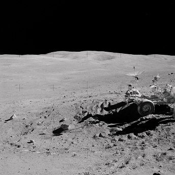 Apollo 16 Foto-Nr. AS16-110-17959: Mondauto
                        im Vordergrund in der Steinwüste an einem
                        Abhang, der "North-Ray-Krater" im
                        Hintergrund