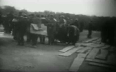 Arriving German prisoners of war, one with
                        a big peace of cardboard (17min. 15sec.)