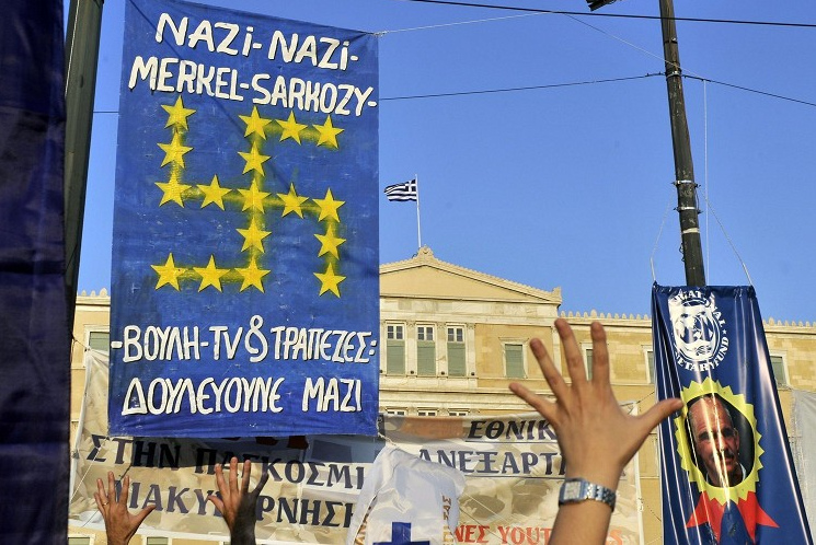 Griechenland, Demonstration mit
                einem Transparent gegen Merkel und Sarkozy als Nazis und
                einer EU-Fahne mit den EU-Sternen als Hakenkreuz,
                Totalansicht (Foto von AFP aus dem Artikel)