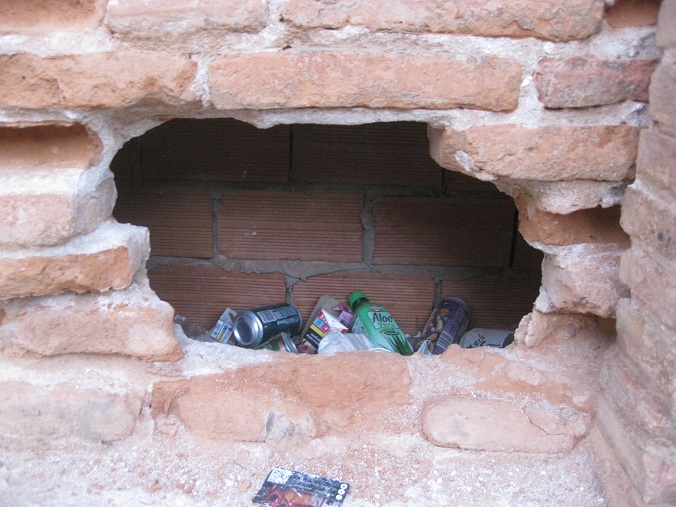 Alcal�
                cerca de Madrid: muro de ladrillos derrumbado con un
                agujero y basura dentro