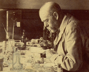 Robert Koch with a microscope in the
                        background, in 1880 appr.